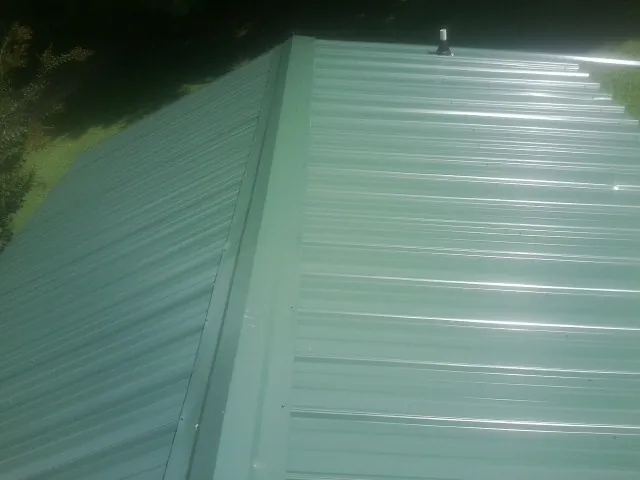 New green metal panels meeting at the ridge of a roof — Flat Roof Repair work by our crew in Tampico