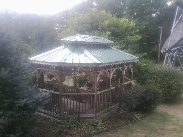Green metal roof on a backyard gazebo surrounded by garden beds in Tampico