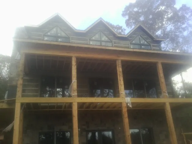 Dormers and porch framing on a large log home under construction — Roof Coating work by our crew in Tampico