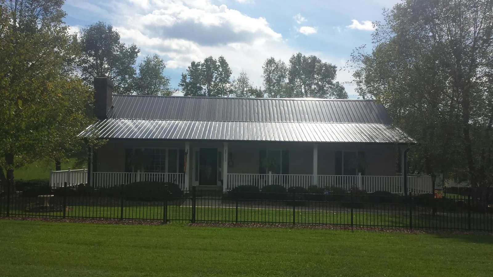 Gray metal roof on a brick ranch with a full width front porch — Gutter Guard Installation work by our crew in Tampico