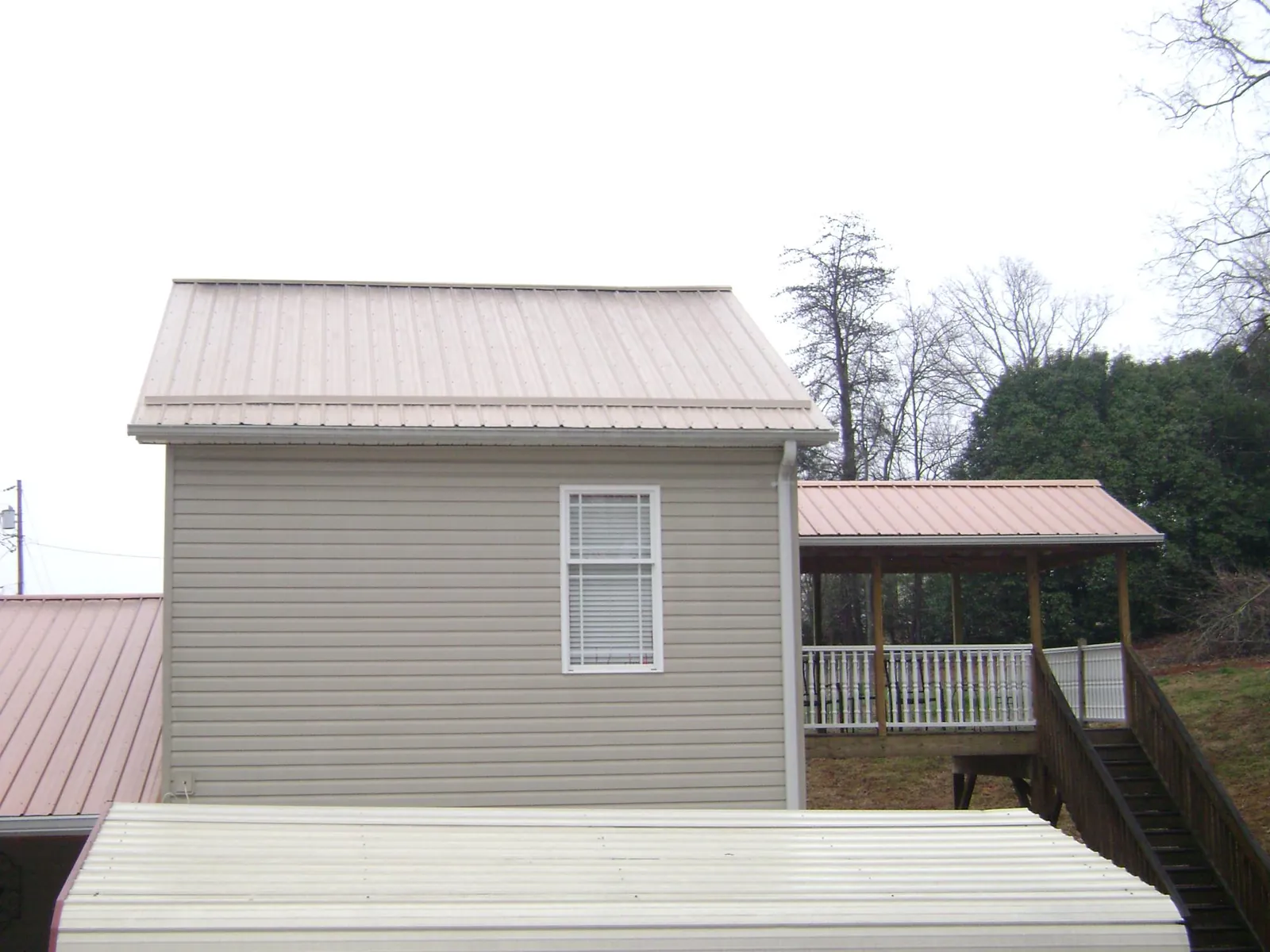 Tan metal roofs on a two story addition and attached porch, from a Roof Replacement job in Tampico