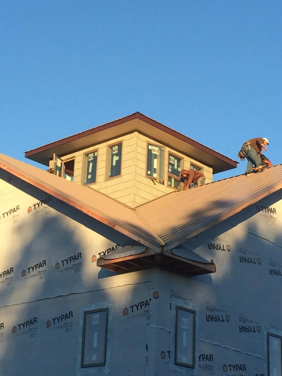 Roofers working around a rooftop cupola on a new metal roof at sunset — Roof Waterproofing in Tampico by Roofing Brothers